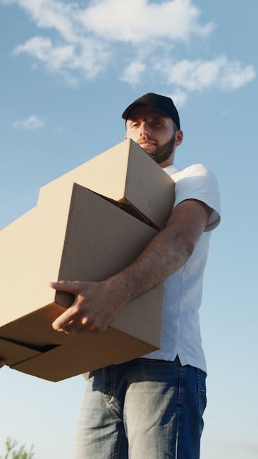 Inside a property, a professional removals team from Colliers Wood Man and Van is engaged in a home relocation, preparing for furniture transport and packing tasks. Visible are several cardboard boxes